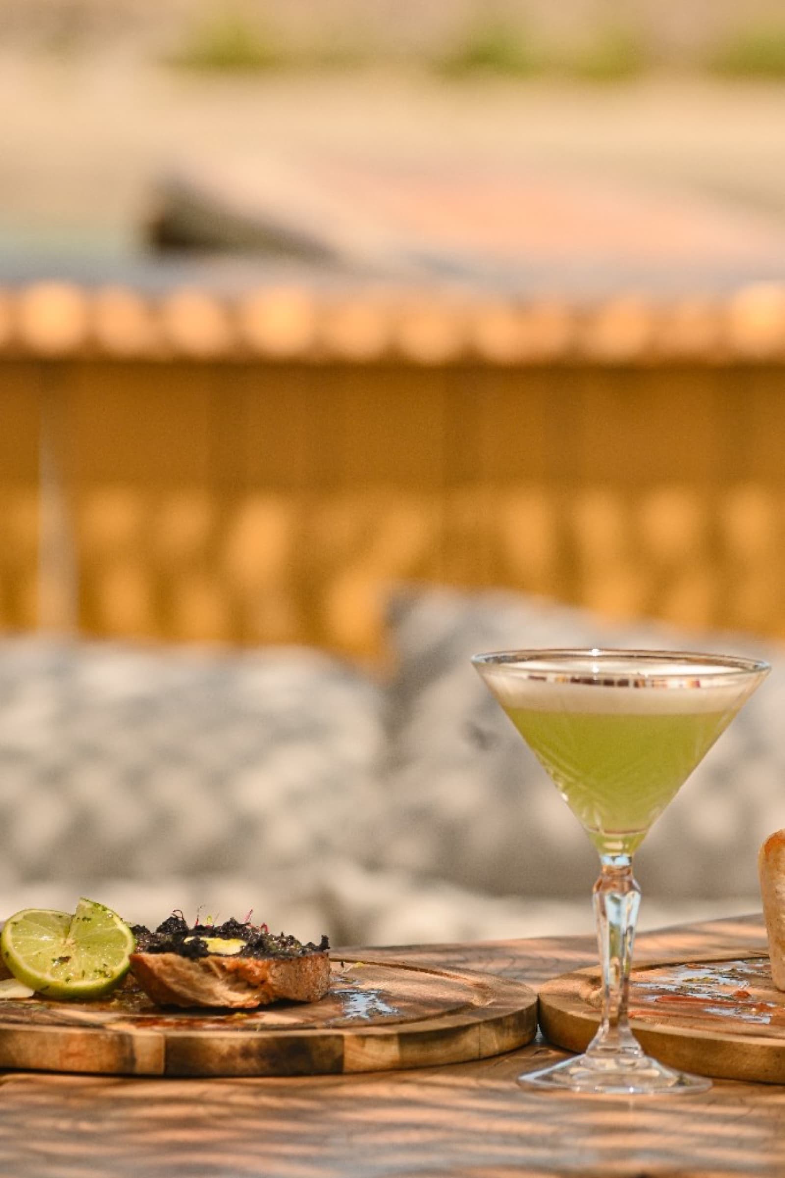 Cocktail vert mousseux et tapas sur terrasse ombragée